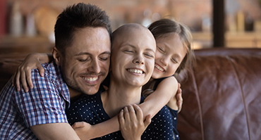 Photo of family smiling; woman is cancer patient.